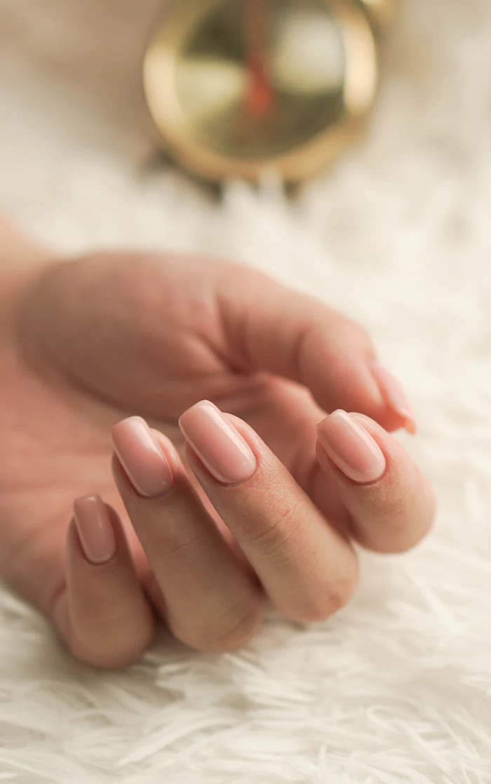 Mleczny, beżowy manicure na tle białego futerka